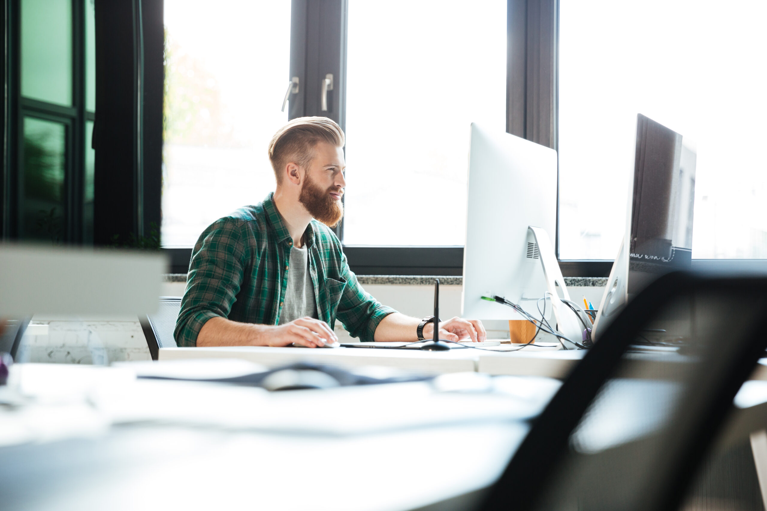 Picture of young handsome man work in office using computer. Looking aside.